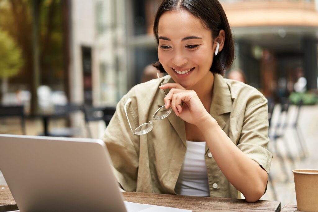 Smiling young woman looks at her laptop screen