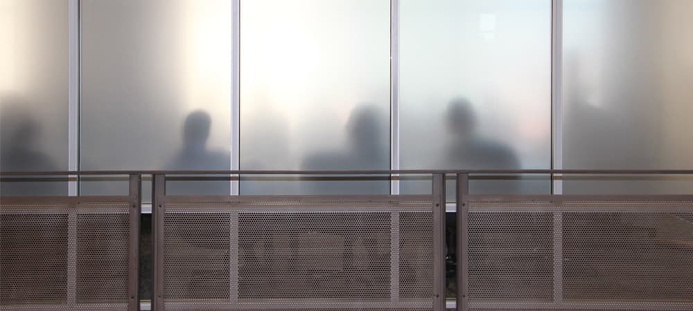 A committee meets in an office with a frosted glass wall.