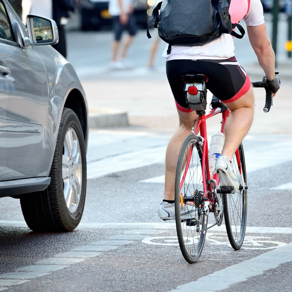 A cyclists rides in a bike lane next to a car.