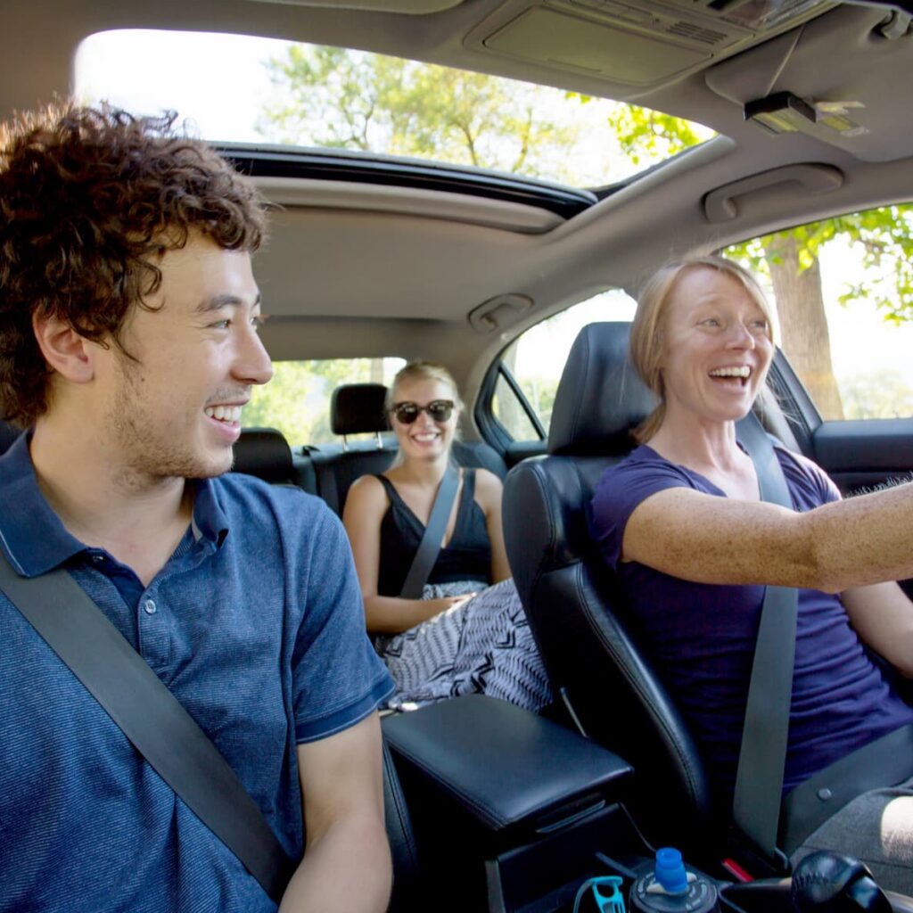 Three individuals smiling while carpooling to work.