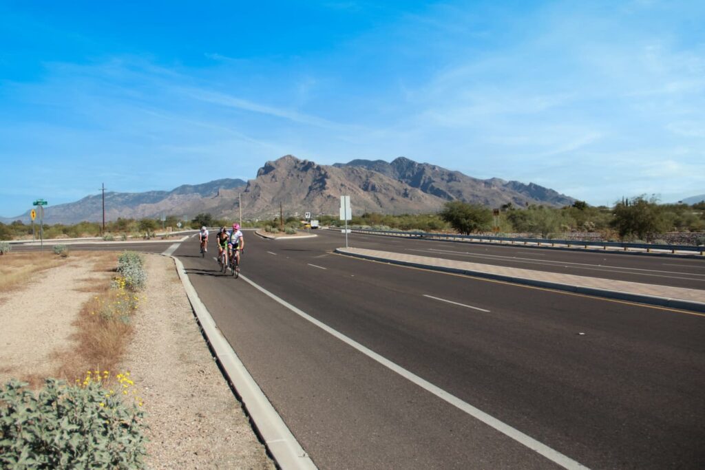 Three cyclists use a dedicated bike lane in Tucson, AZ with Mt. Lemmon in the background.