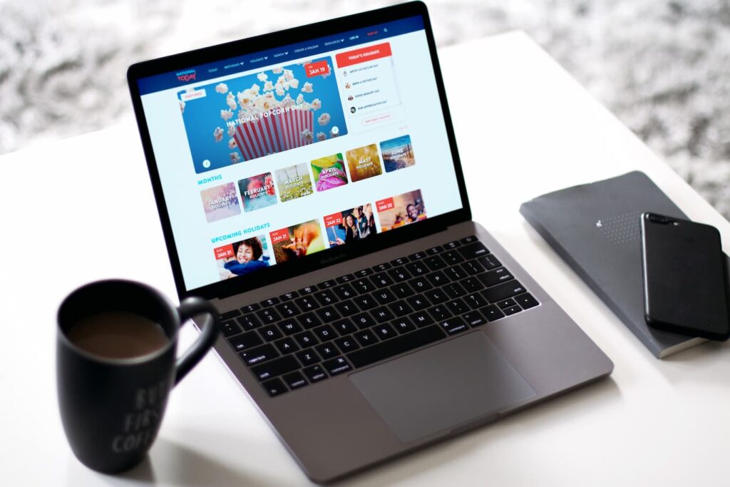 NationalToday website is visible on a laptop screen next to a cup of coffee.
