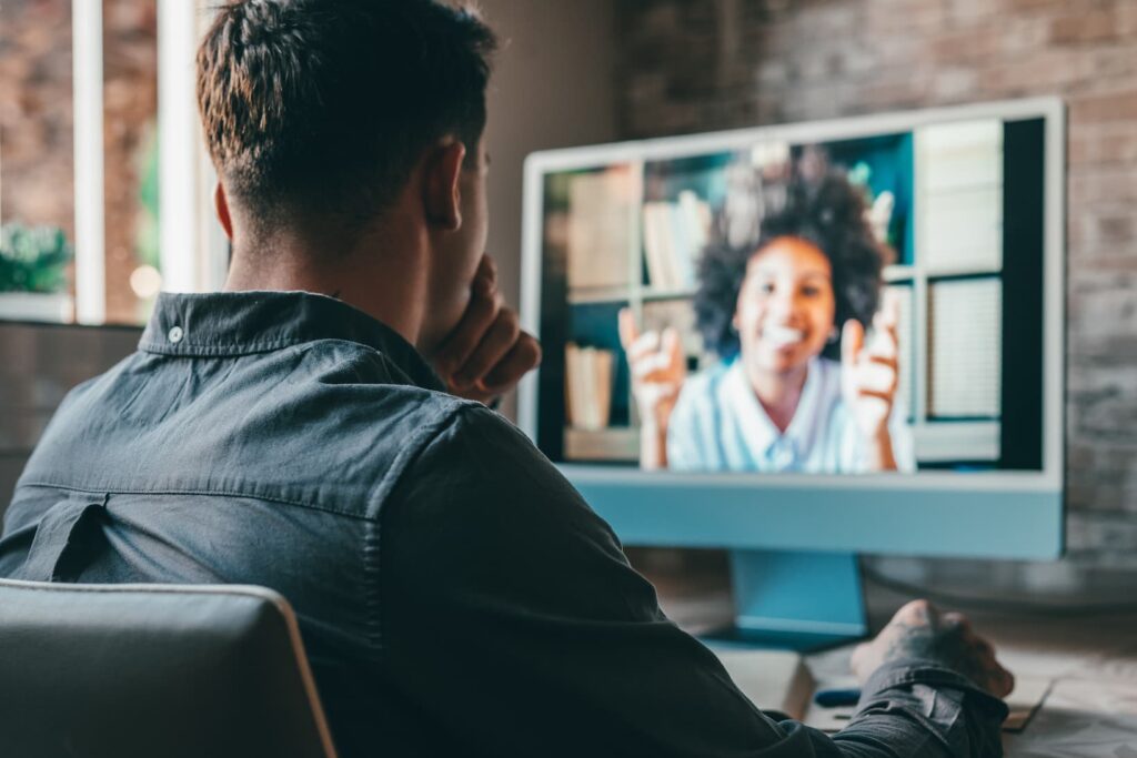 A man watches a presenter on a Zoom video call.