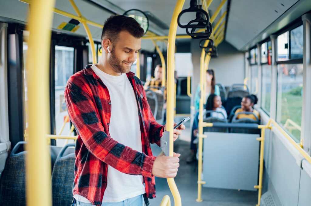 Man on a bus listens to music on his earbuds.