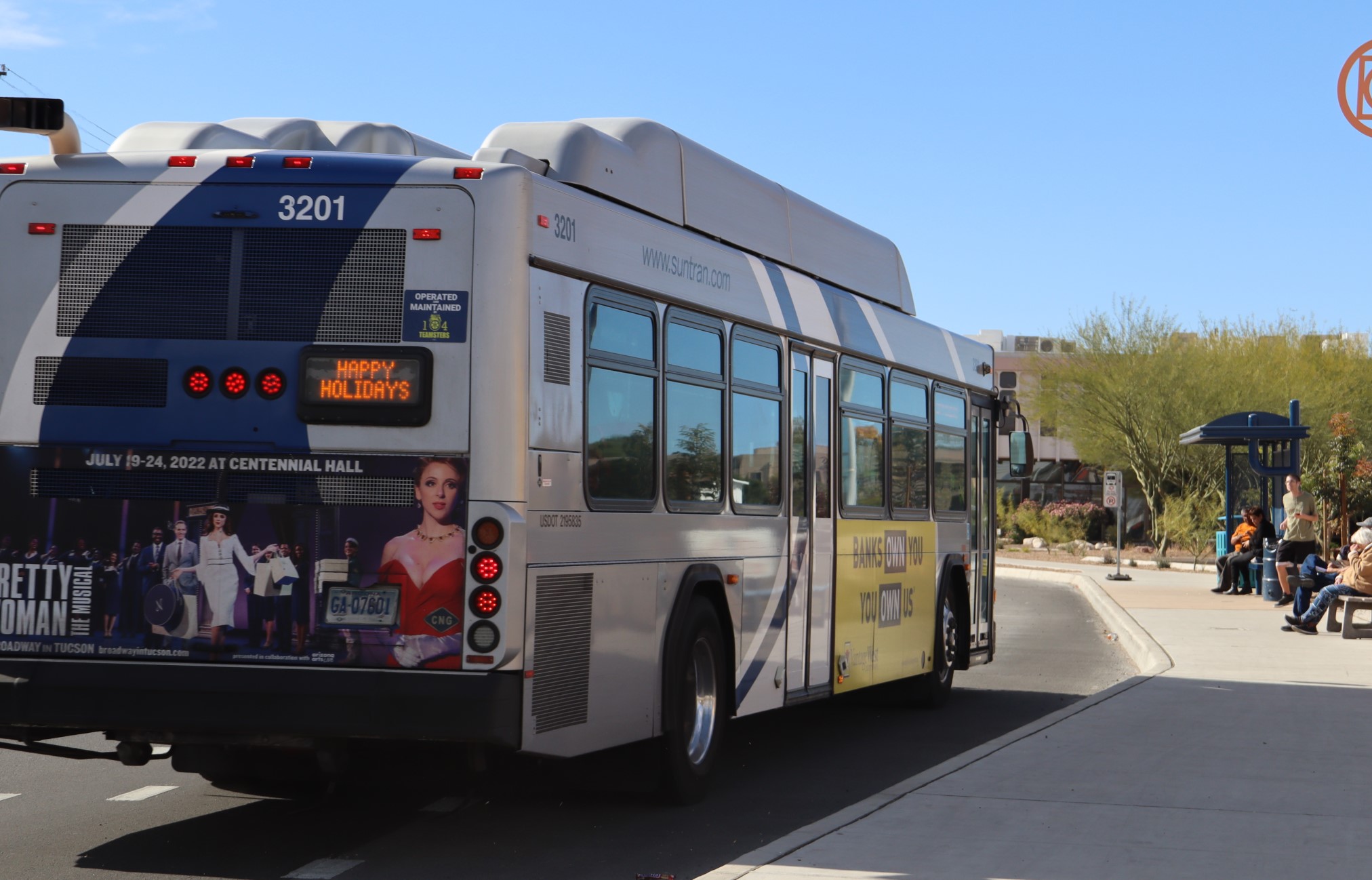 Public bus pulls up to a bus stop.