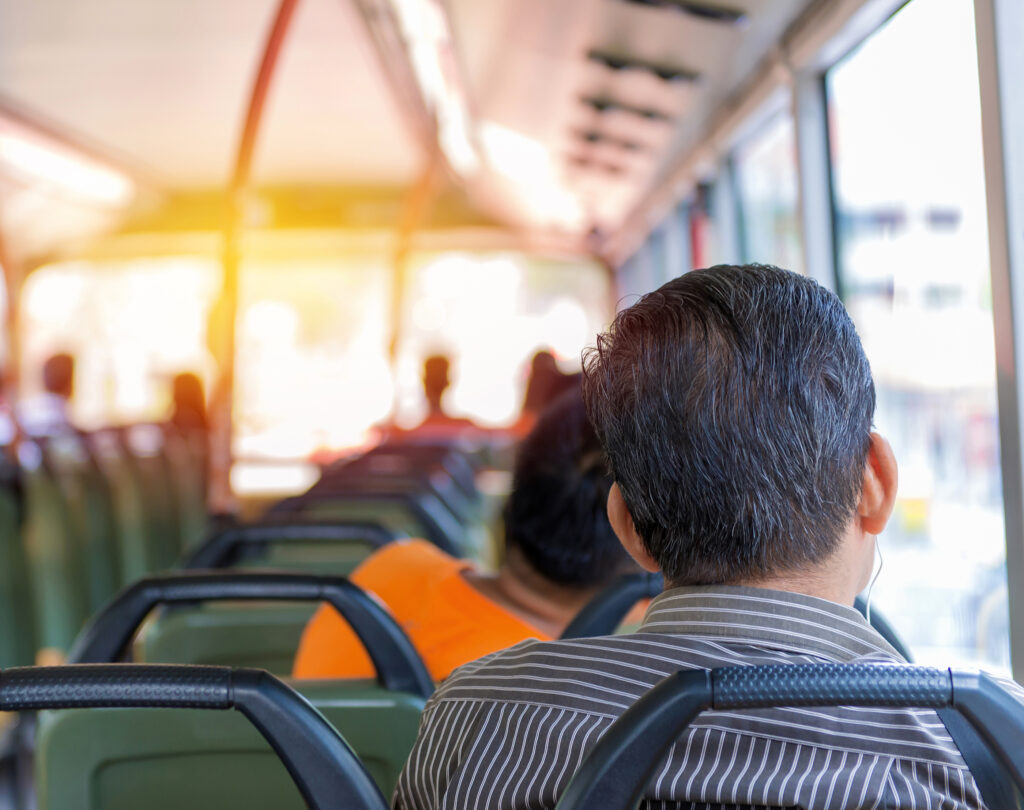 A man looks out the window of his bus while commuting to work.