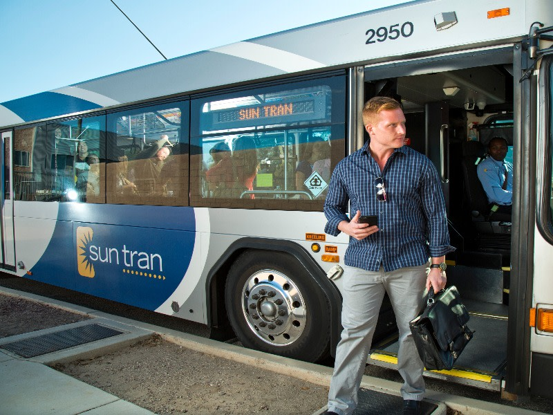 Man carrying briefcase steps out of a Sun Tran bus.